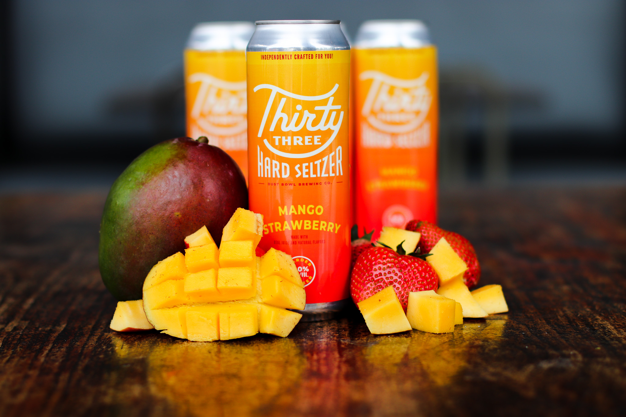 Picture of Thirty Three Seltzer Strawberry Mango can with fresh cut mangoes and strawberries
